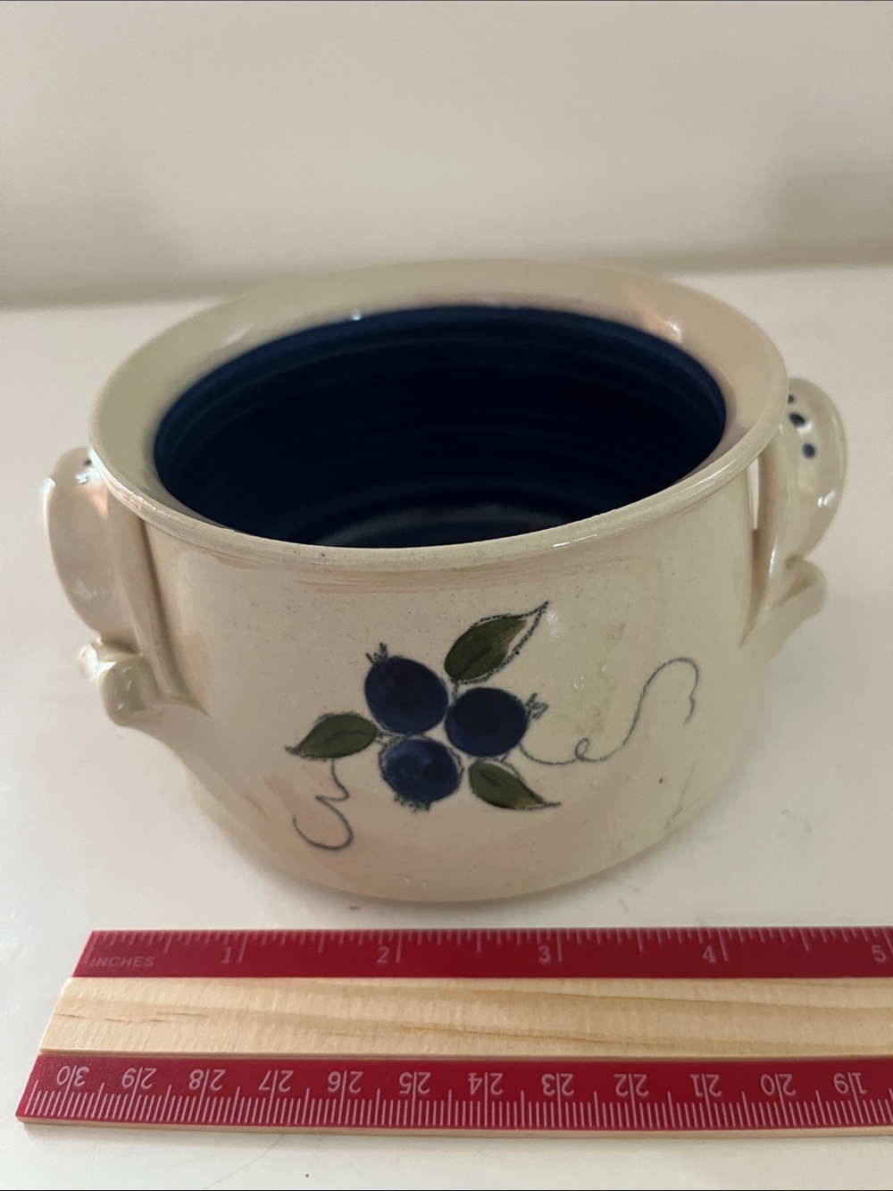 Unique handmade pottery bowl with blue interior and blueberry design